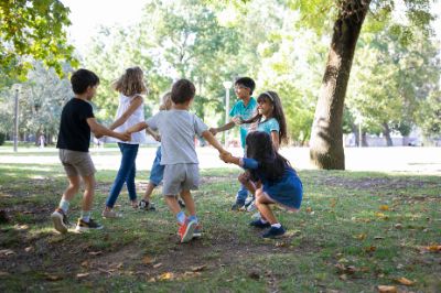 bambini-felici-che-giocano-insieme-all-aperto-ballano-sull-erba-si-godono-attivita-all-aperto-e-si-divertono-nel-parco-concetto-di-festa-o-amicizia-per-bambini