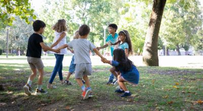bambini-felici-che-giocano-insieme-all-aperto-ballano-sull-erba-si-godono-attivita-all-aperto-e-si-divertono-nel-parco-concetto-di-festa-o-amicizia-per-bambini